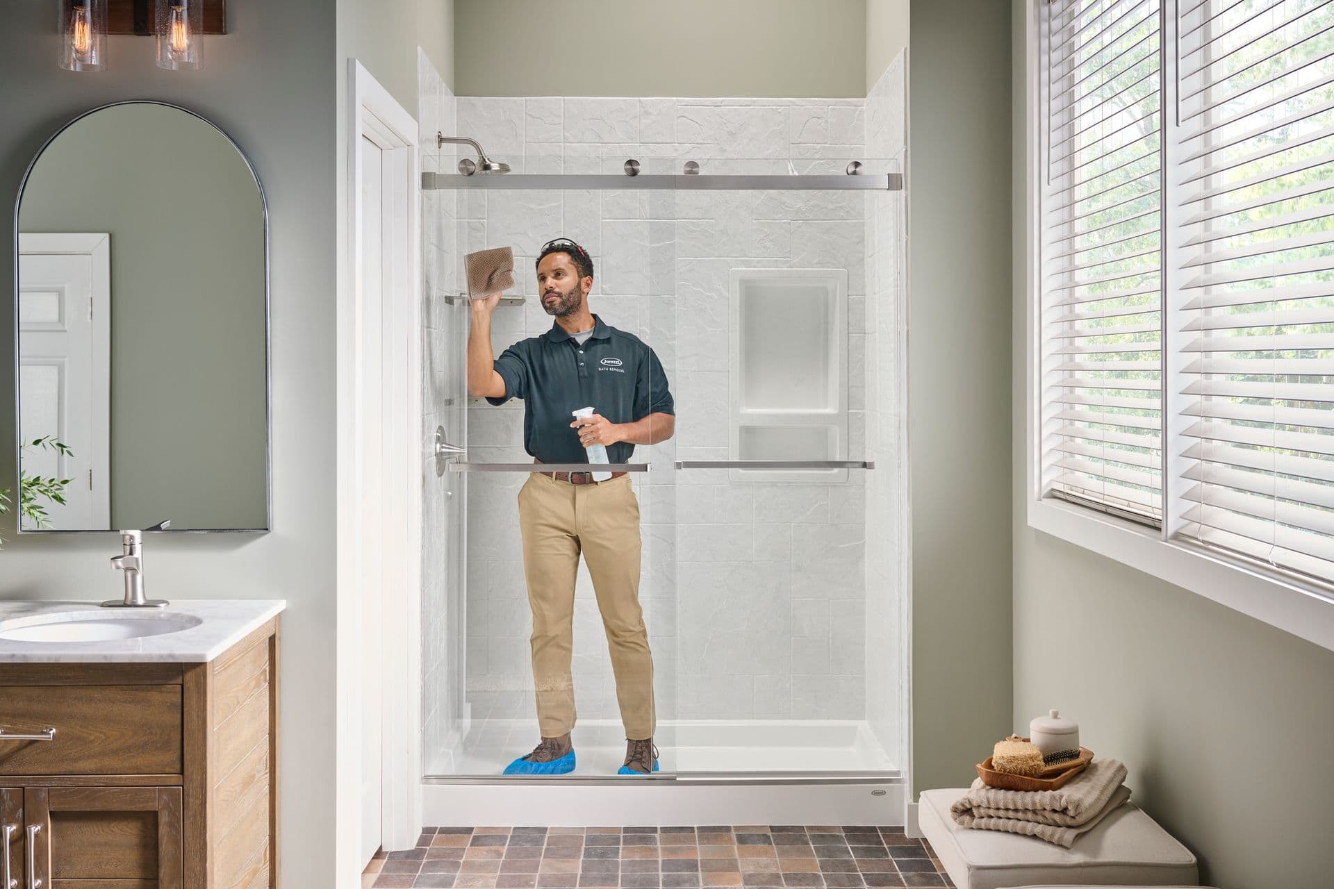 A worker cleans glass sliding doors of a newly-installed walk-in shower.