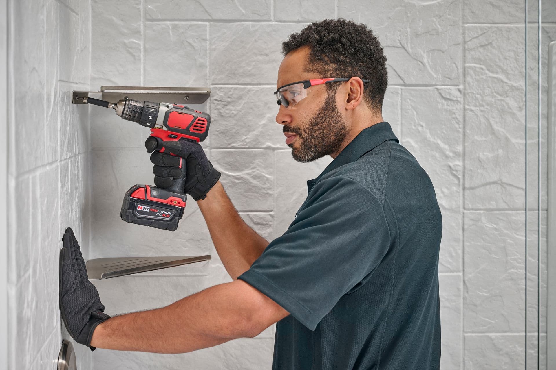 A worker installs corner shelves in a shower.